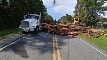 log truck jackknifed load spilled on roadway