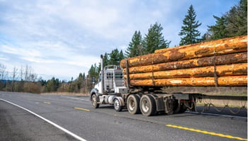 Log truck traveling on roadway