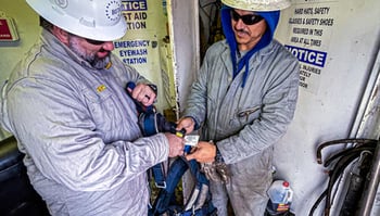 Oil & gas workers adjusting personal safety harnesses
